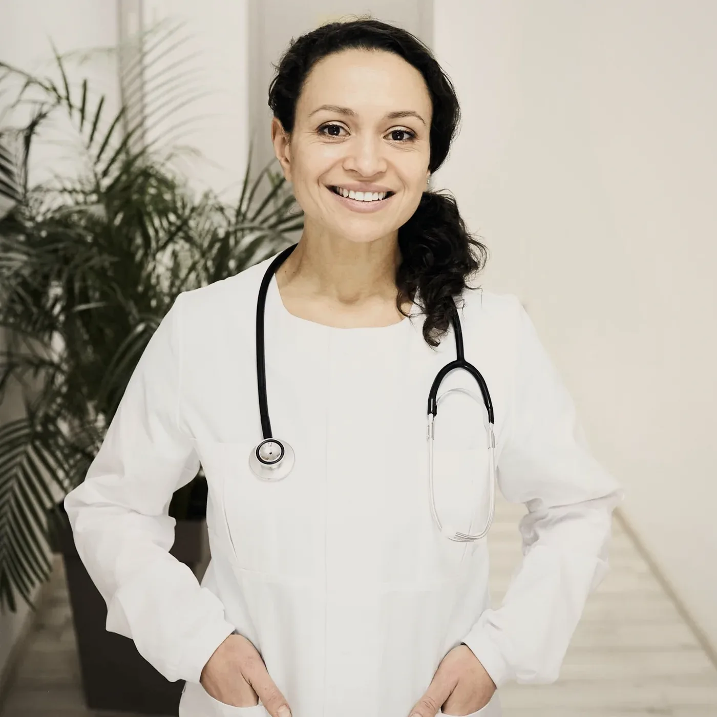 A smiling woman in a white coat with a stethoscope.