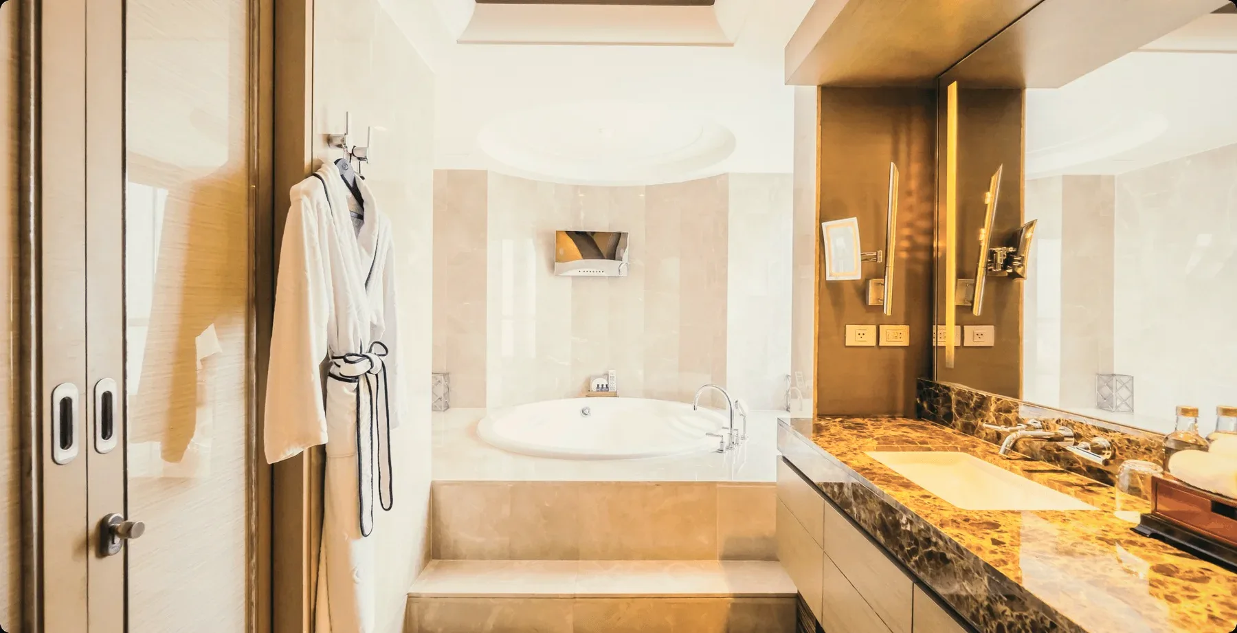 A marble bathroom with a bathrobe on a hook.