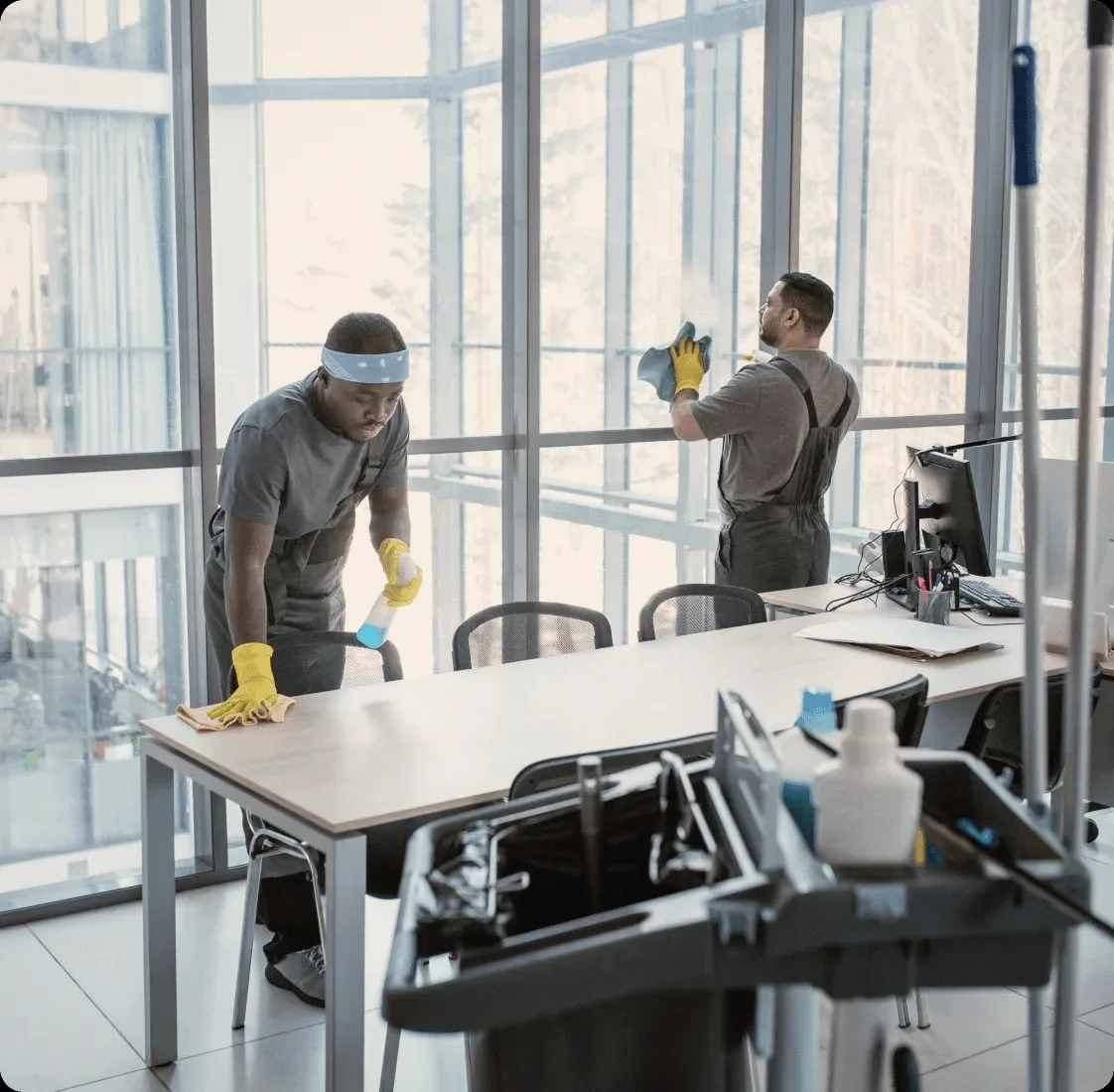 Two cleaners at the windows of a glass office.