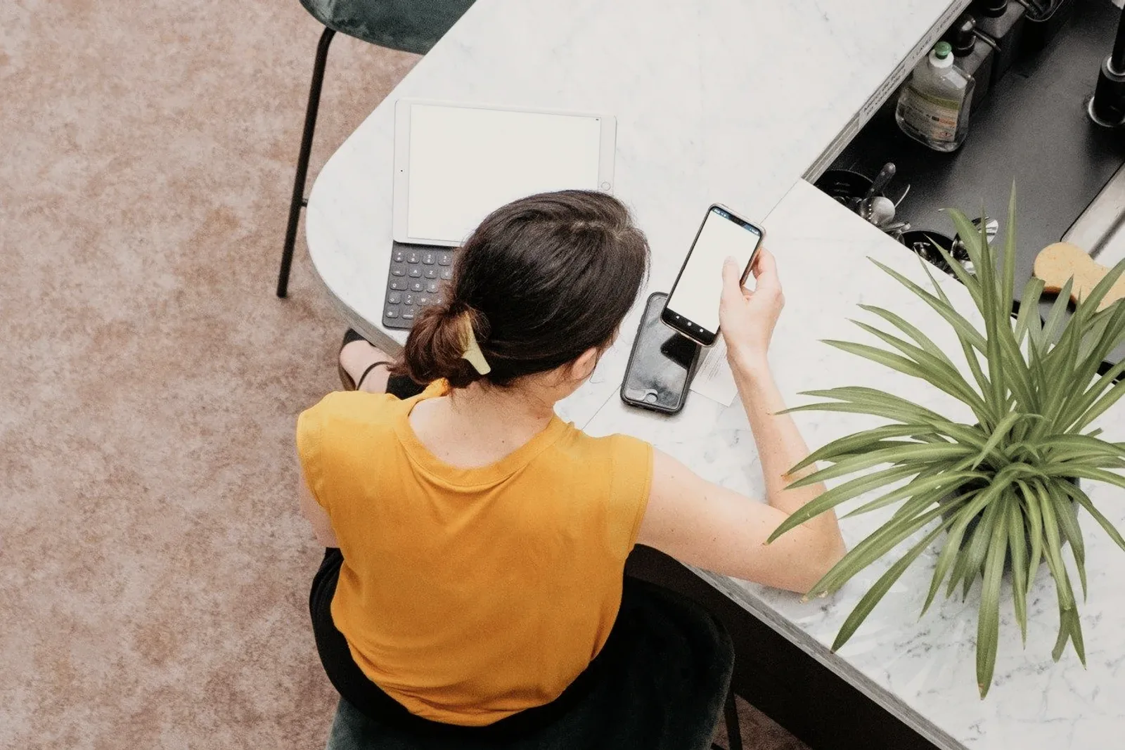 A person in a yellow top at a marble desk, seen from above.
