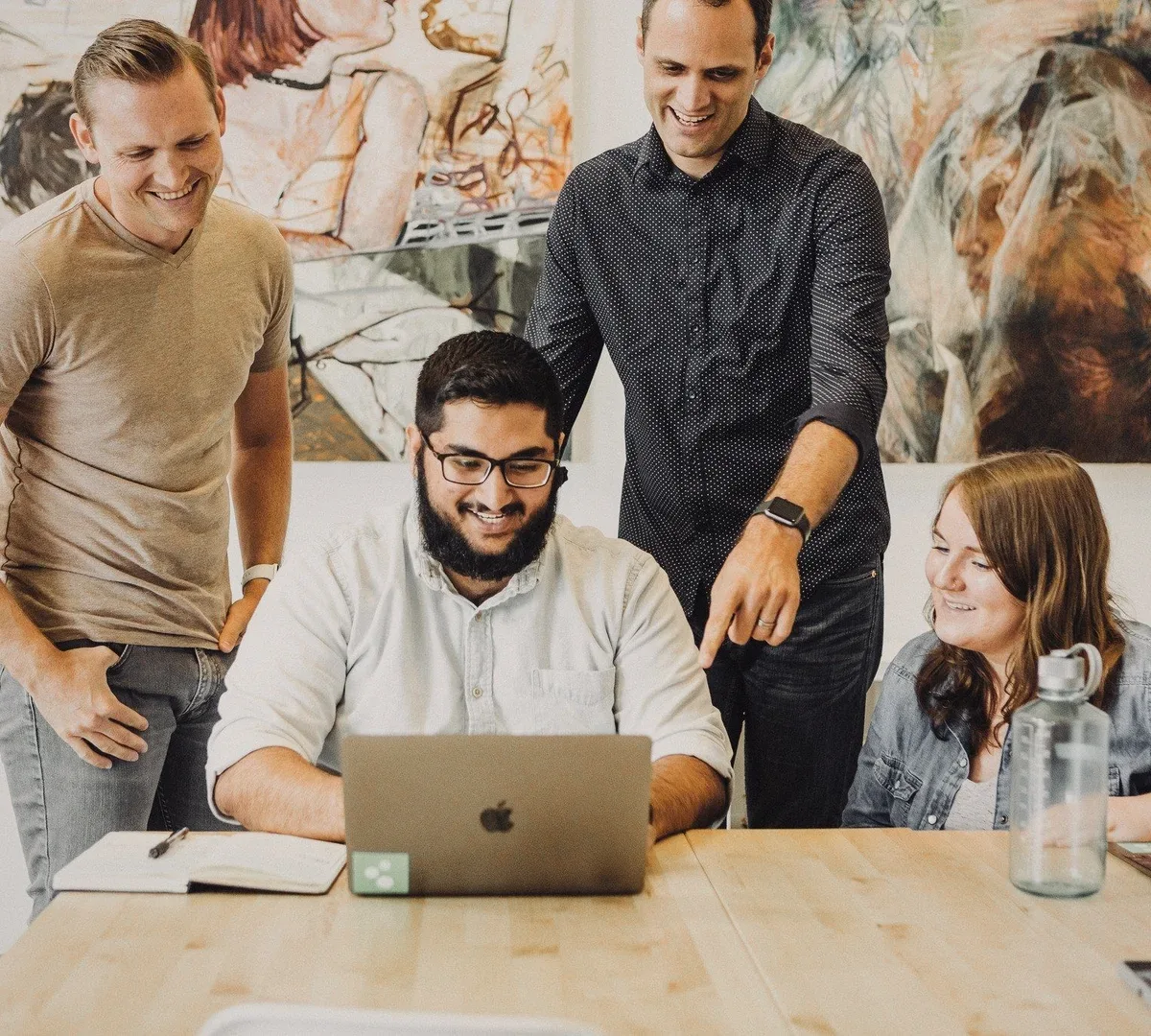 Four colleagues around a laptop.