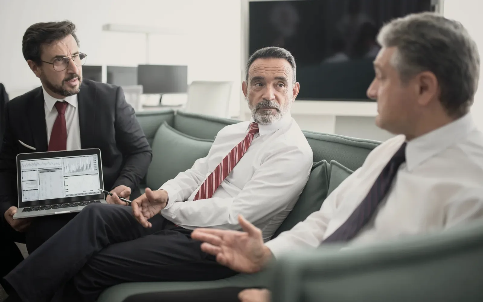 Three men at a table with papers.
