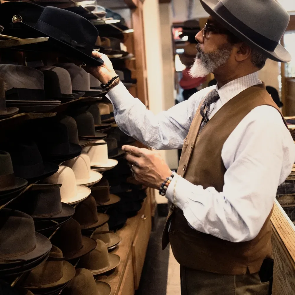 A man in a hat at a shop rail.
