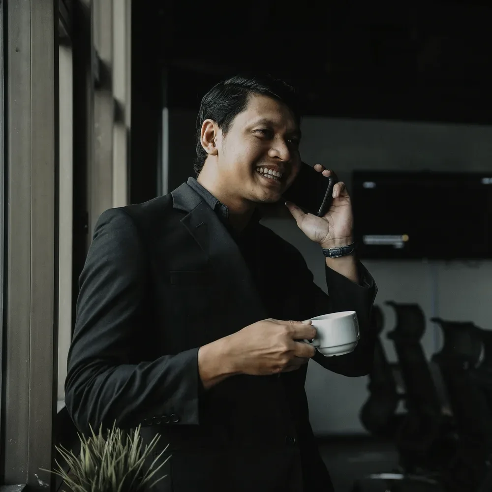 A man on the phone with a coffee.
