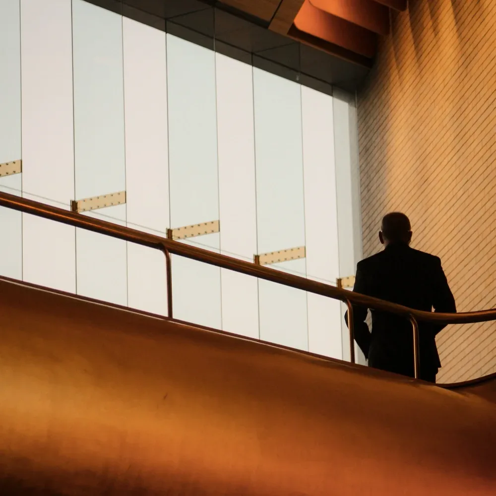 A man at a window in an amber hall.