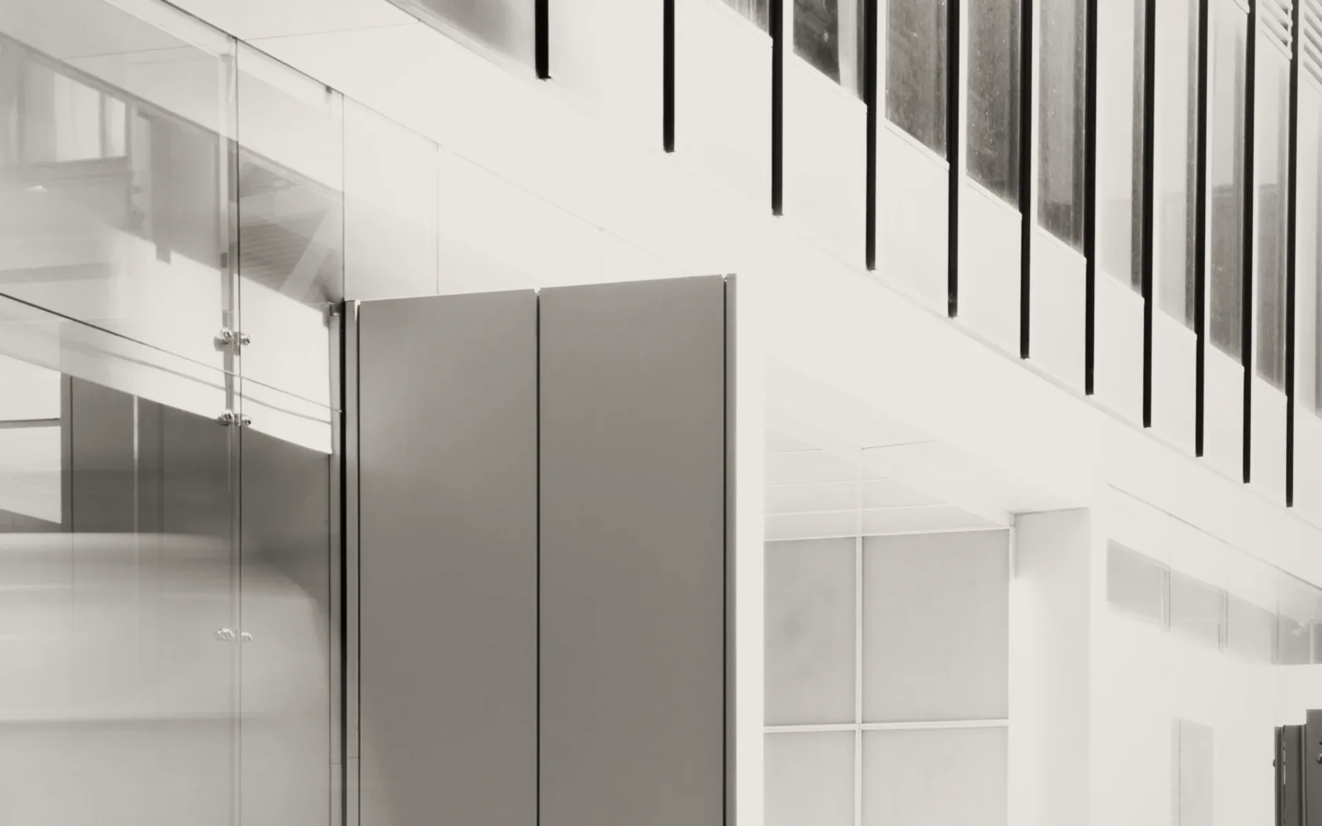 People walking through a glass lobby, in grey.