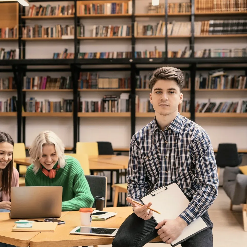 Students at a library table with a laptop.