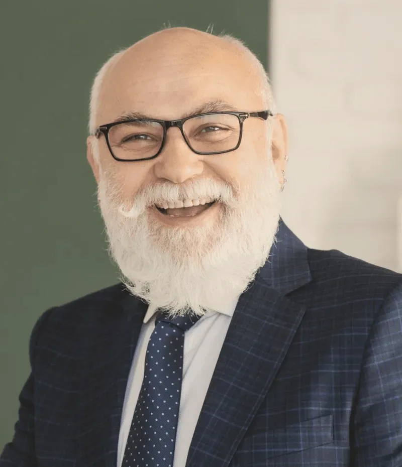 A bearded man in glasses and a suit.