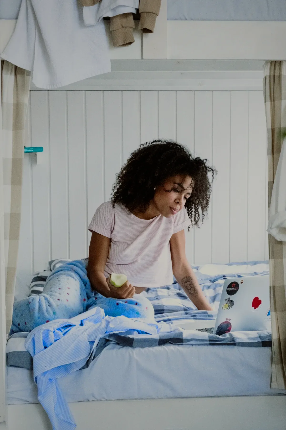 A guest reading on her bunk bed with a laptop.