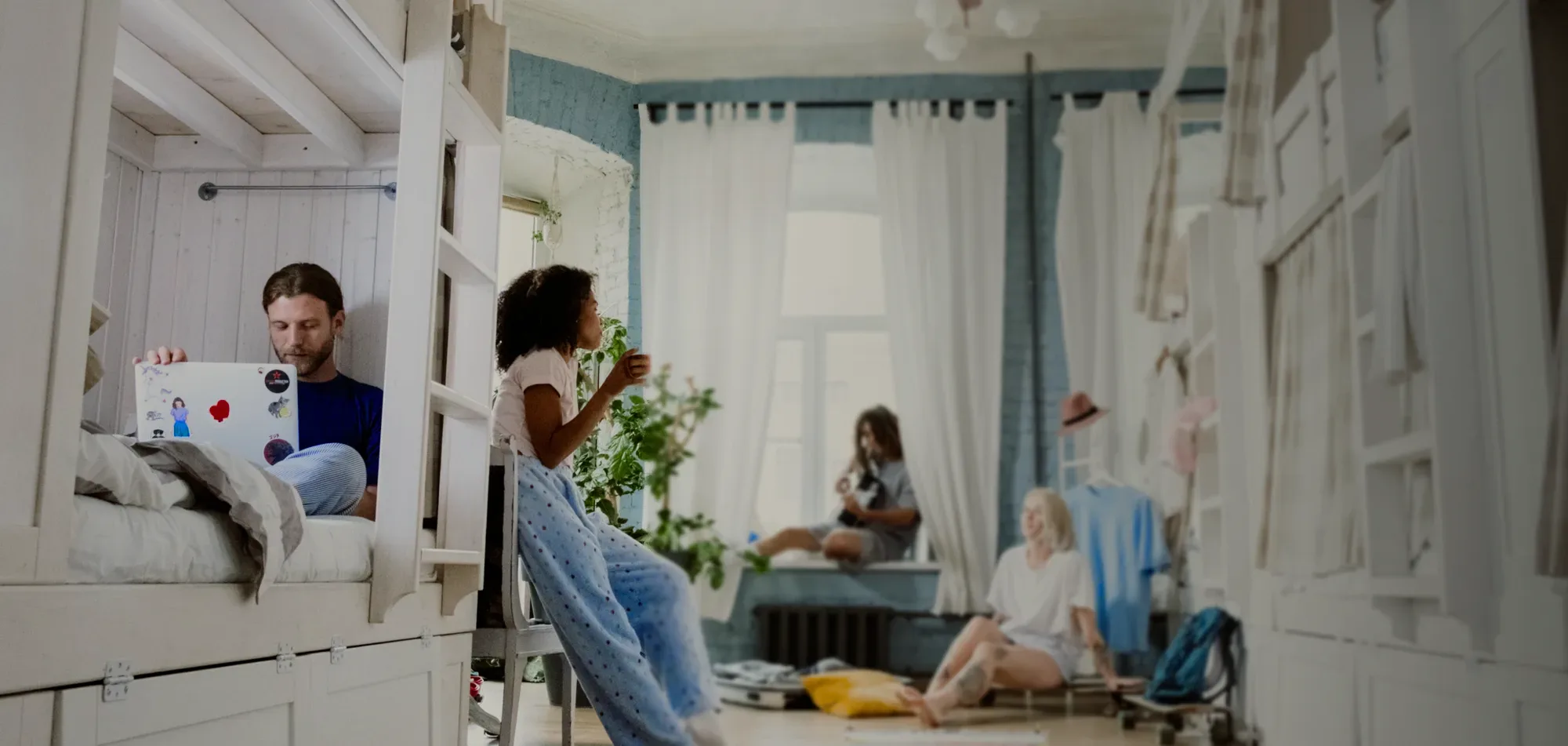 Friends in a sunny dorm with white bunk beds.