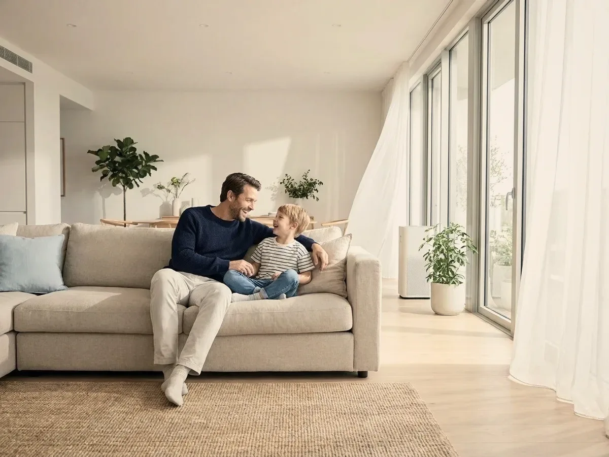 A father and child on a sofa by a window.