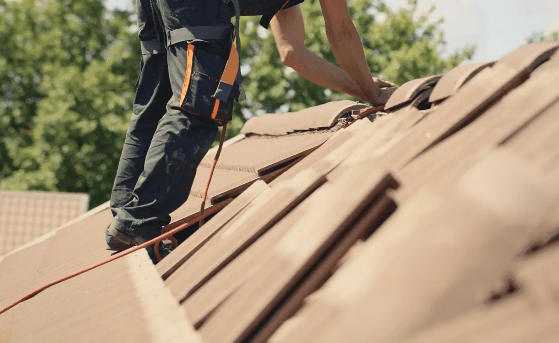 A roofer fitting tiles on a ridge, seen from below.