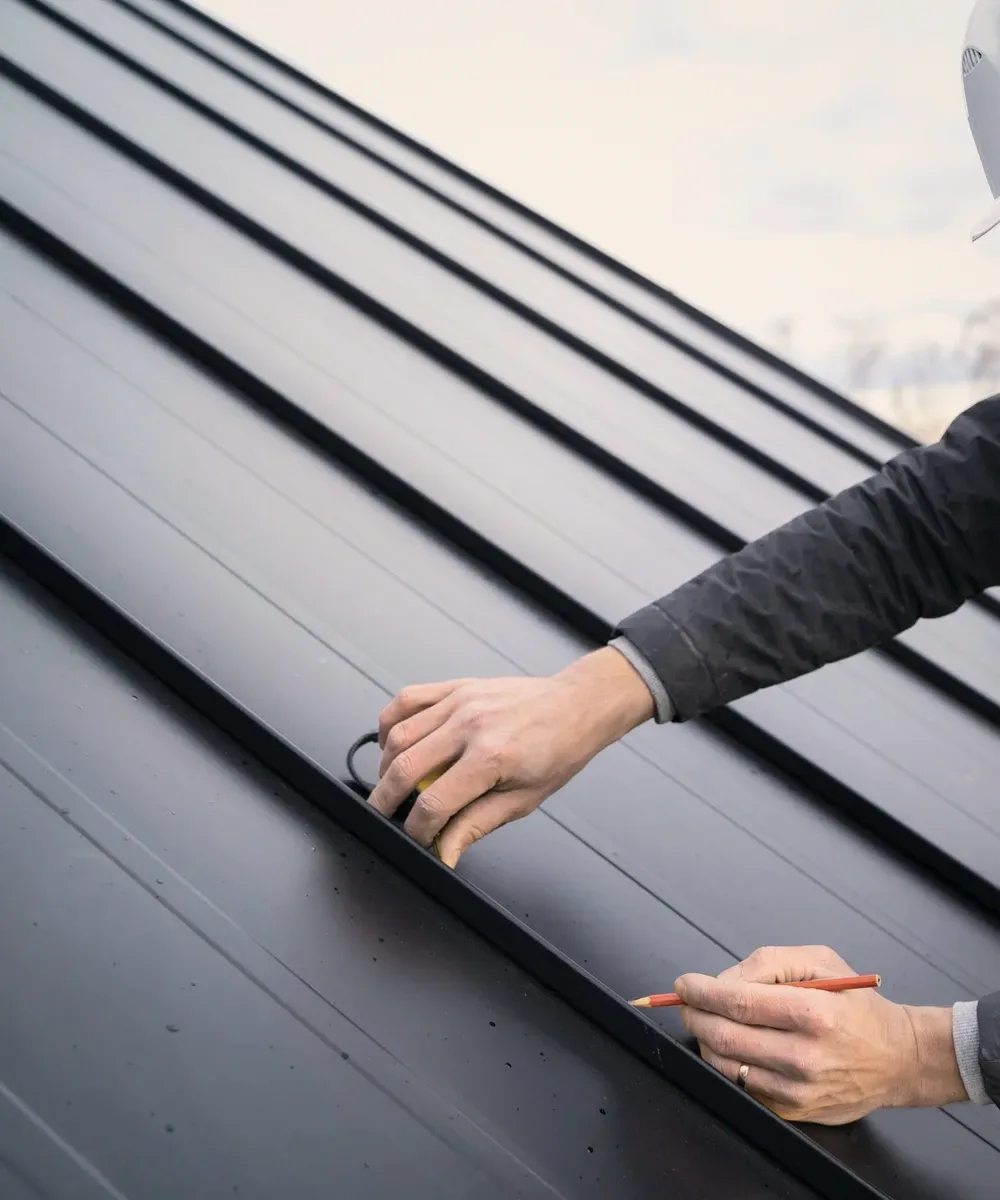 A roofer in a white helmet checking a seam.