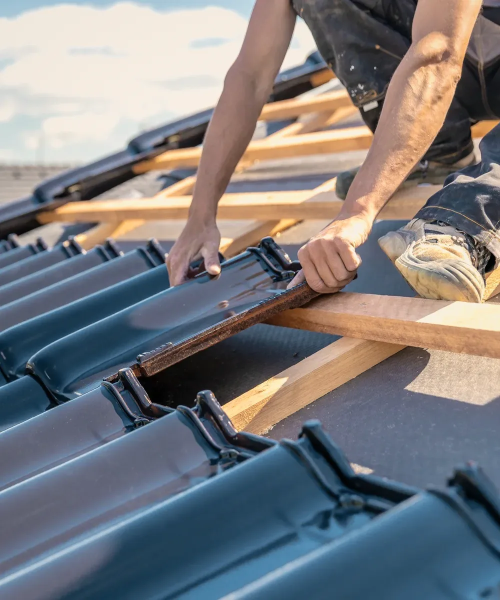 Hands laying blue tiles on battens.