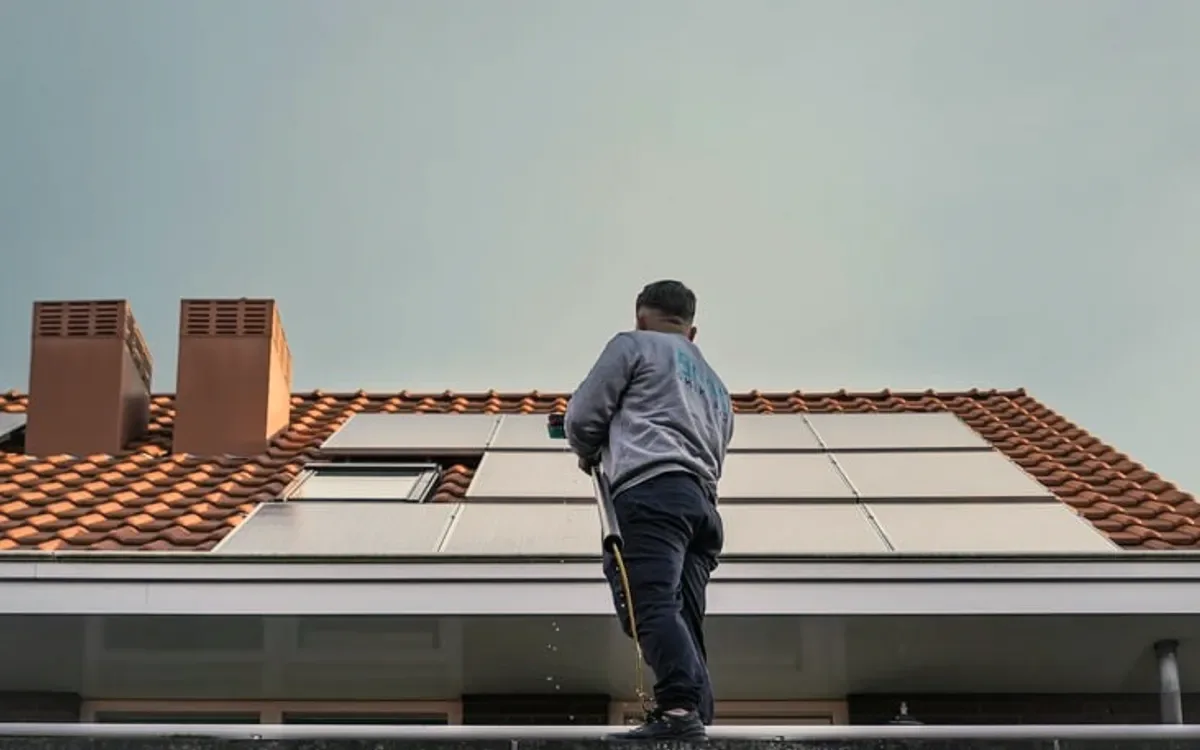 A roofer on a red tiled roof with chimneys.