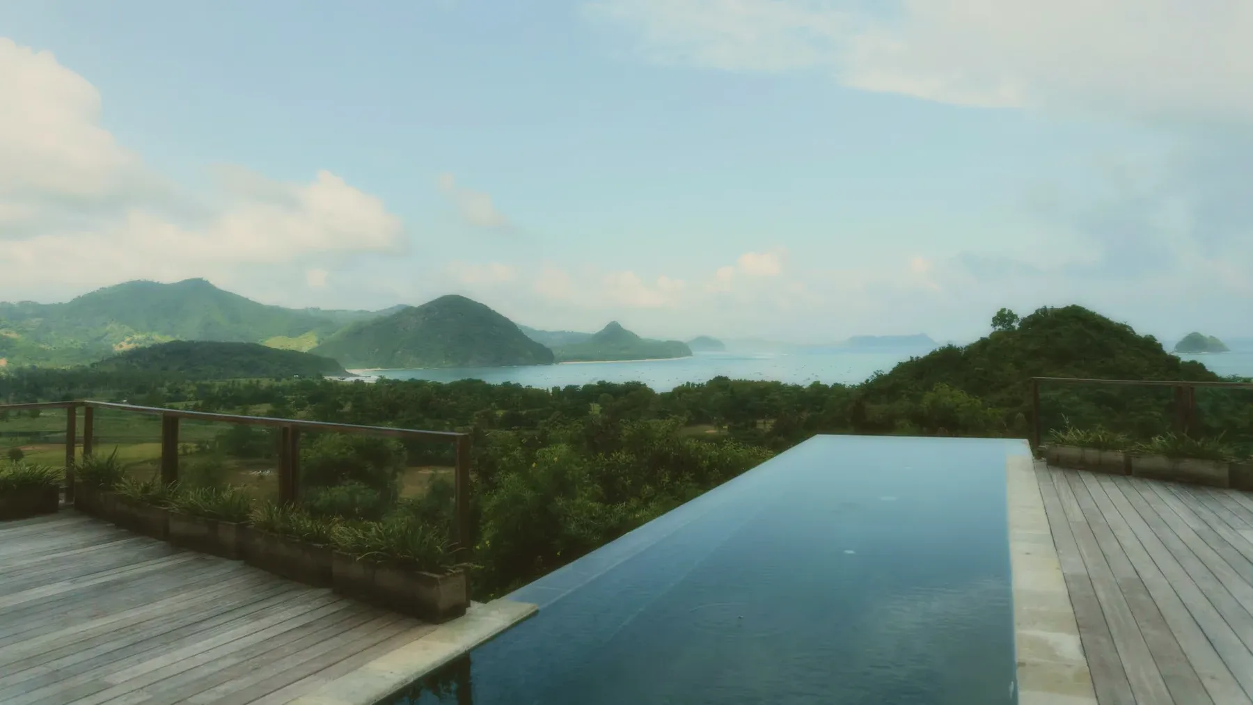 An infinity pool at dusk looking over green hills and the sea.