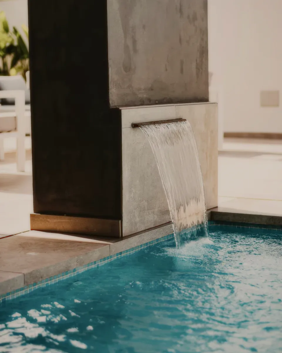 Water pouring from a stone spout into a blue pool.