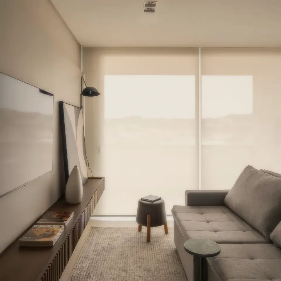 A living room with a grey sofa, a stool and a screen on the wall.