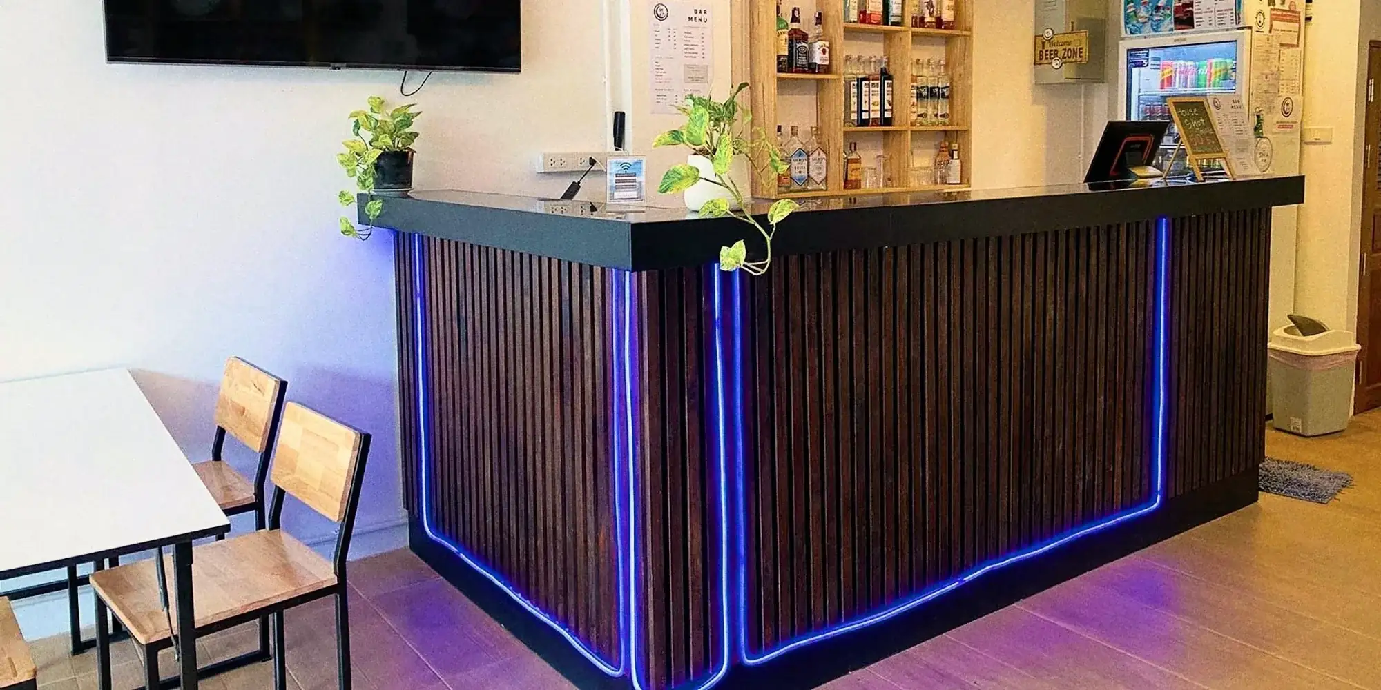 The front desk, lit in blue, with a shelf of drinks behind it.