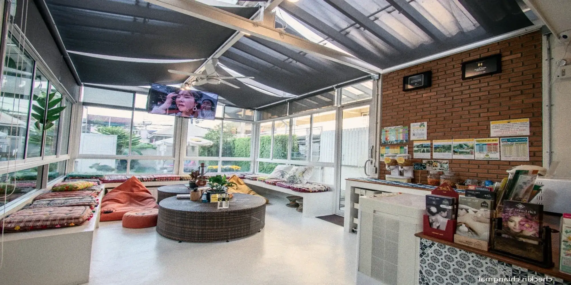 A glass-roofed common room with cushions and a round table.