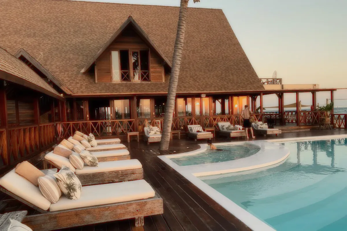 A pool deck with loungers at a wooden villa.
