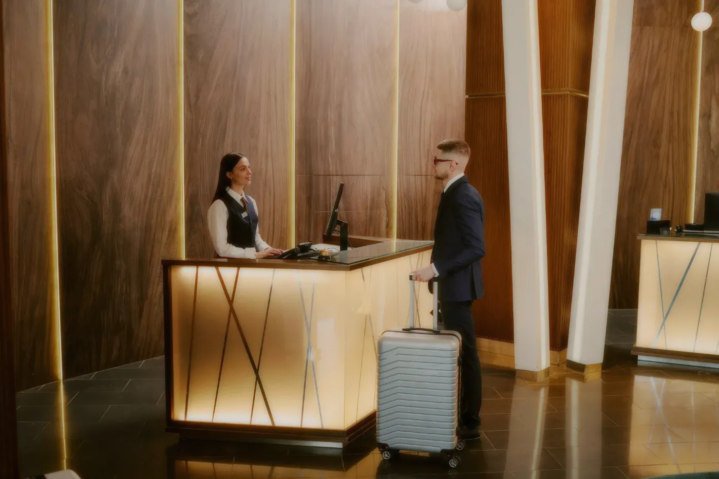 A guest at the reception desk, wood panelling behind.