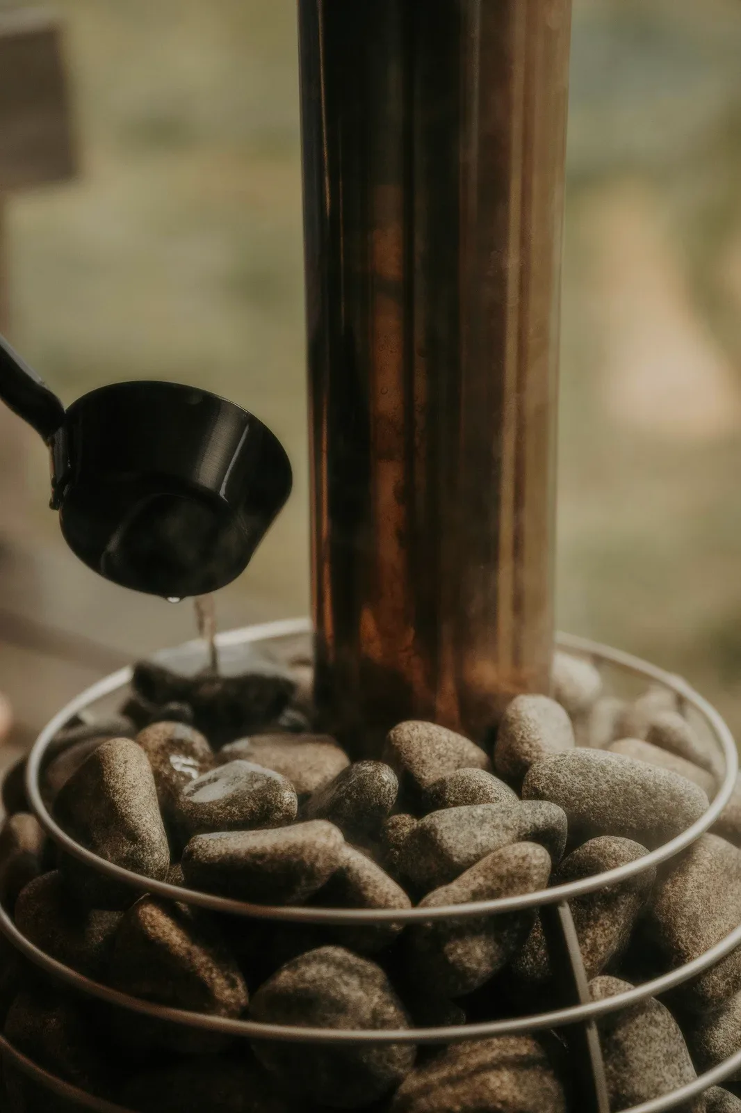 Water poured from a ladle over hot stones.