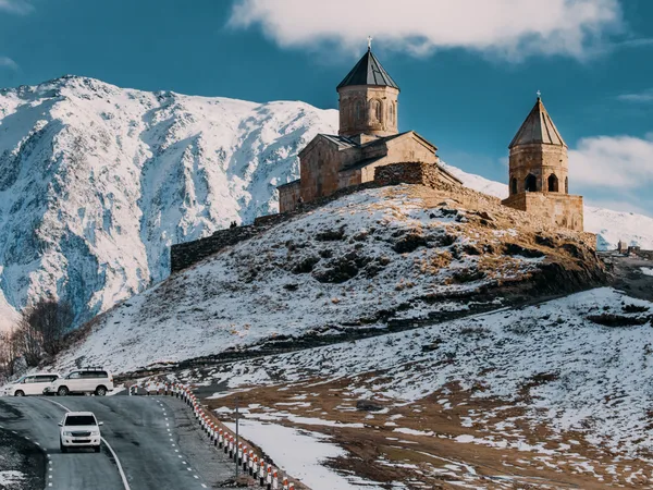 Gergeti church on a hill under snow-covered mountains.