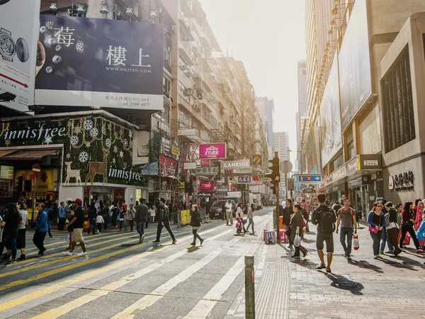 People crossing a street of shop signs in Hong Kong.