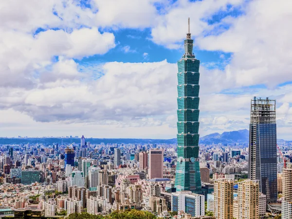 Taipei 101 rising above the city under white clouds.
