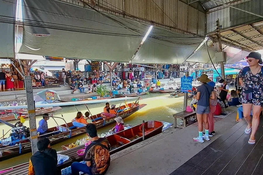 Visitors on the pier of a floating market, above the boats.