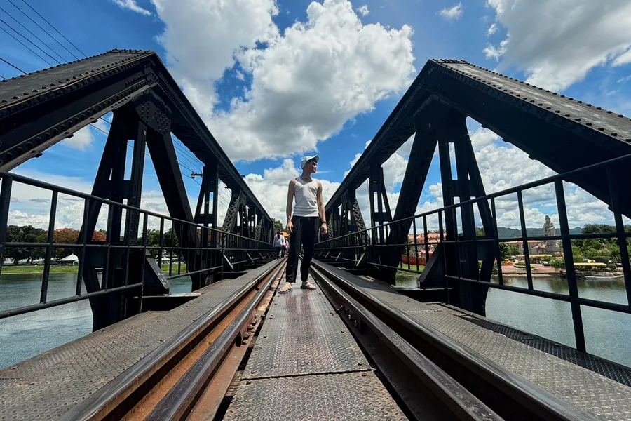 A man standing on the railway bridge over the River Kwai.