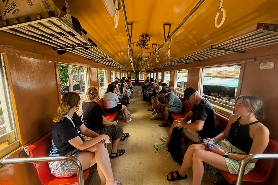 Travellers sitting in an old railway carriage with open windows.