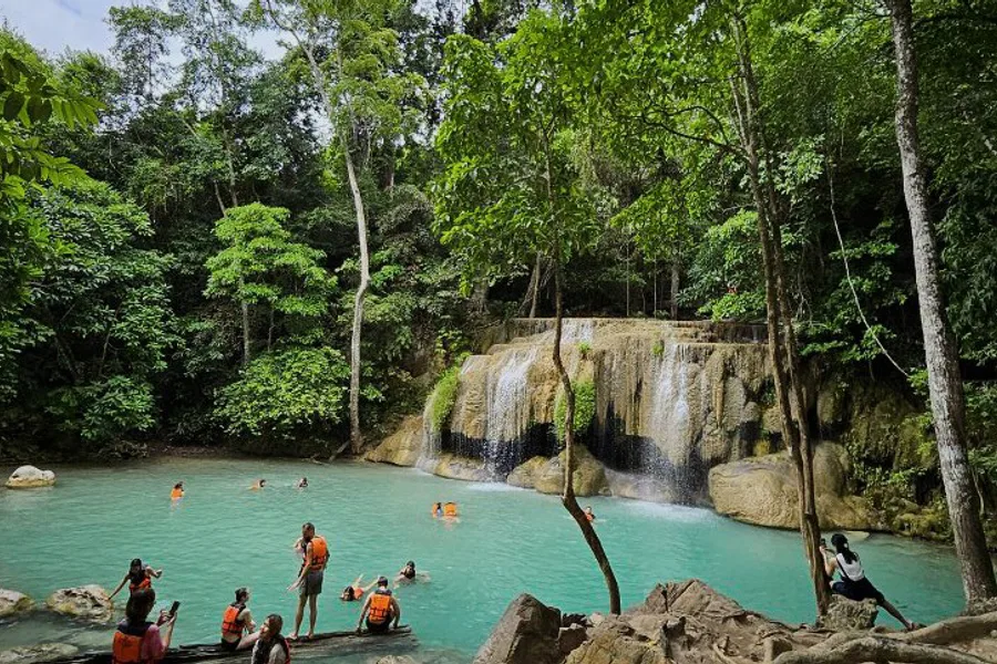 A waterfall with people swimming in the pool below.