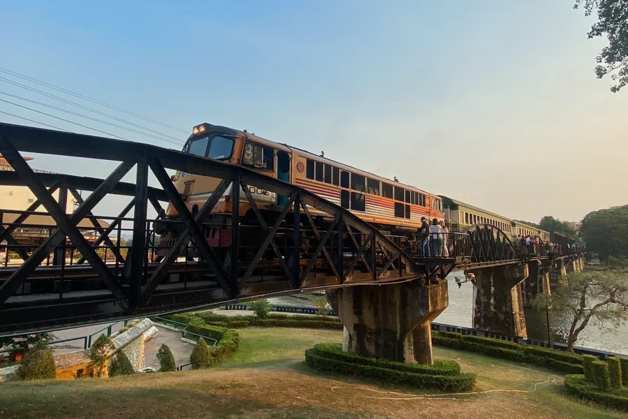 A train crossing the bridge on the River Kwai at dusk.
