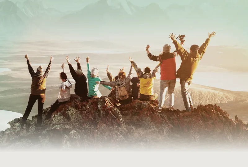 A group of travellers on a hilltop with their arms raised.