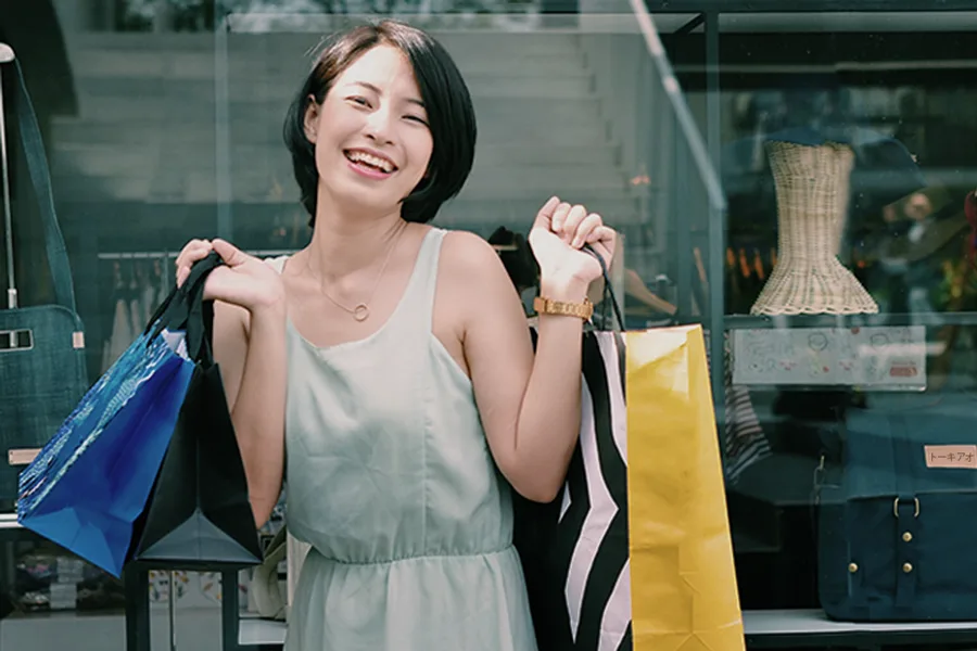 A woman laughing with shopping bags in her hands.