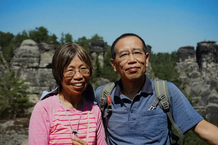 An older couple smiling in front of rock mountains.