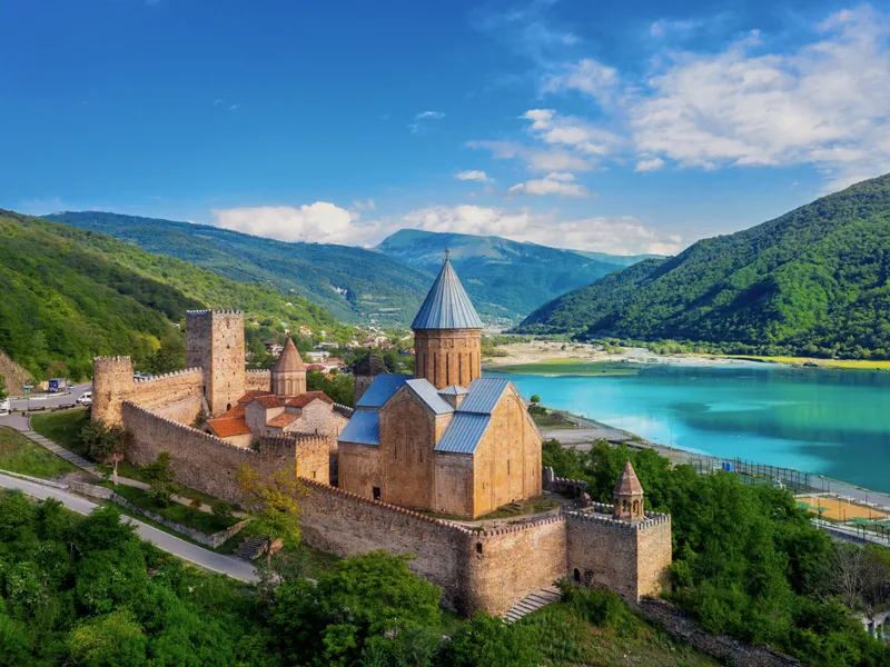 A stone fortress with a church beside a blue lake.