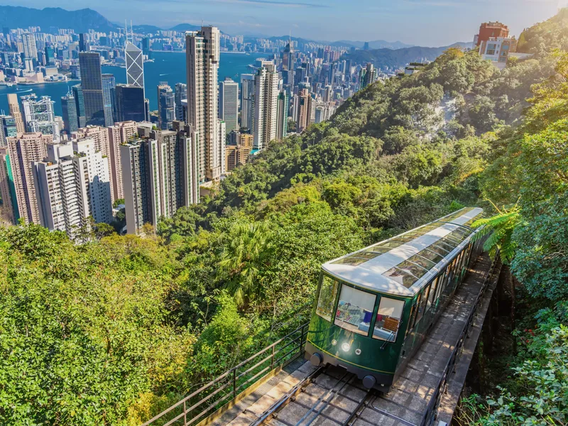 The Peak Tram climbing a green hill above the towers of Hong Kong.