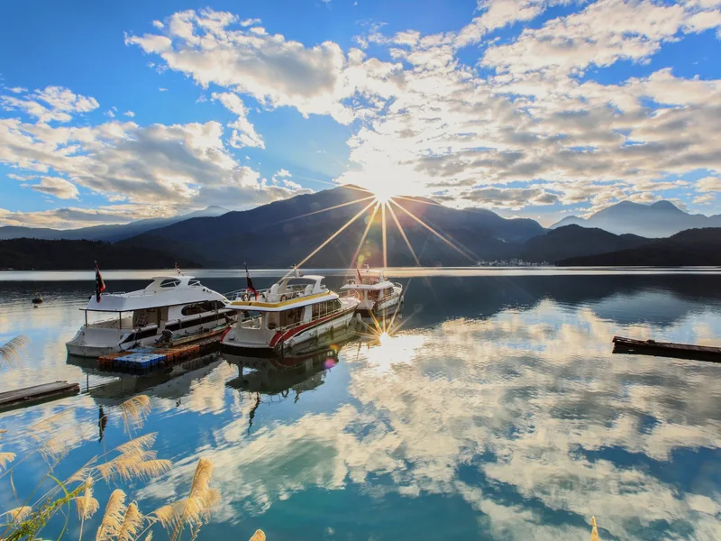 Boats on Sun Moon Lake as the sun rises over the mountains.