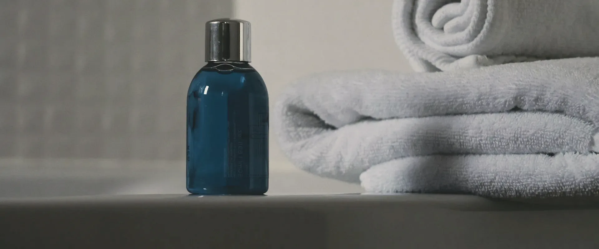 Rolled grey towels and a bottle.