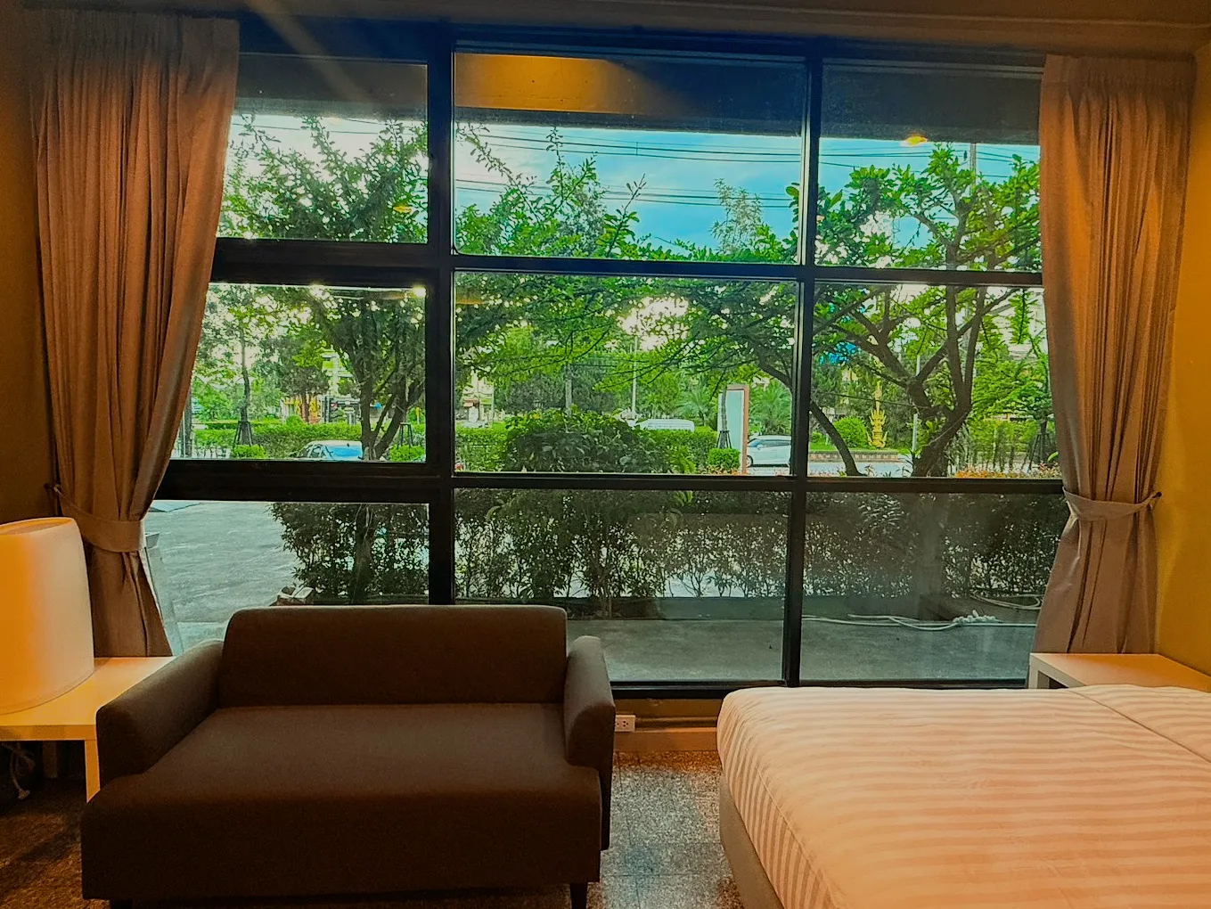 A room's sofa in front of a full-height window onto the garden.
