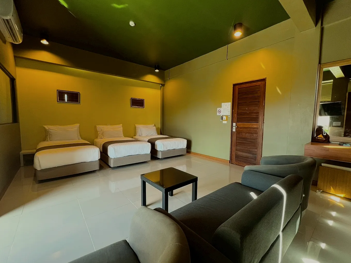 A triple room: three single beds and a lounge corner with a sofa.