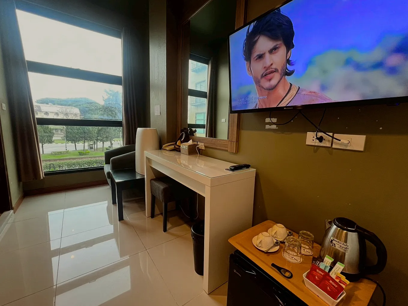 The superior room's desk under a wall-mounted TV, with the kettle and cups.