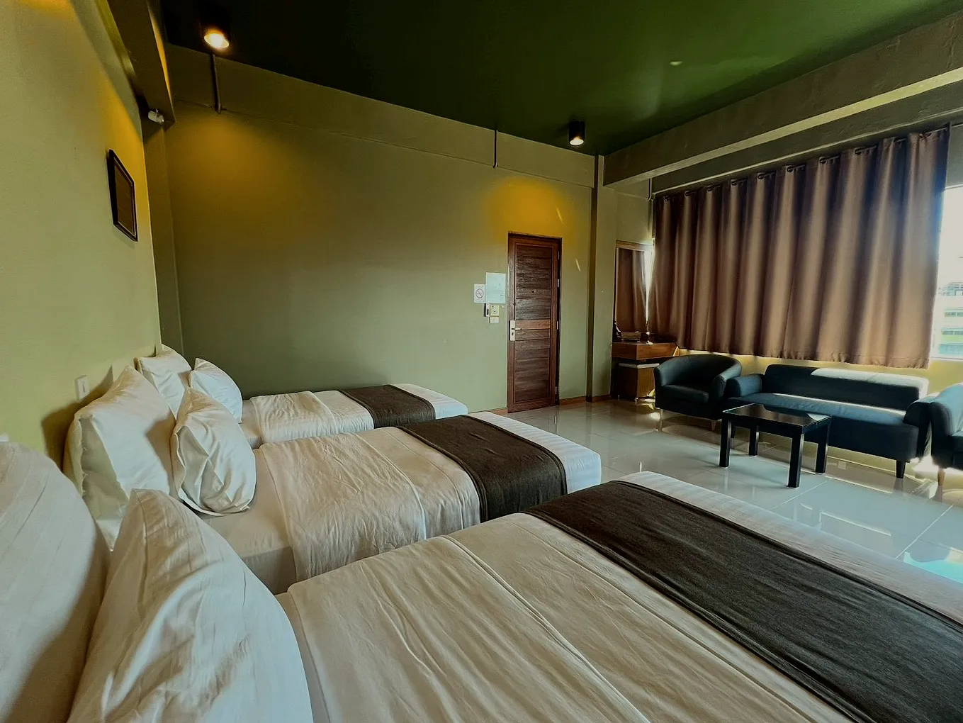 Three beds with white linen and dark runners, seen from the foot.
