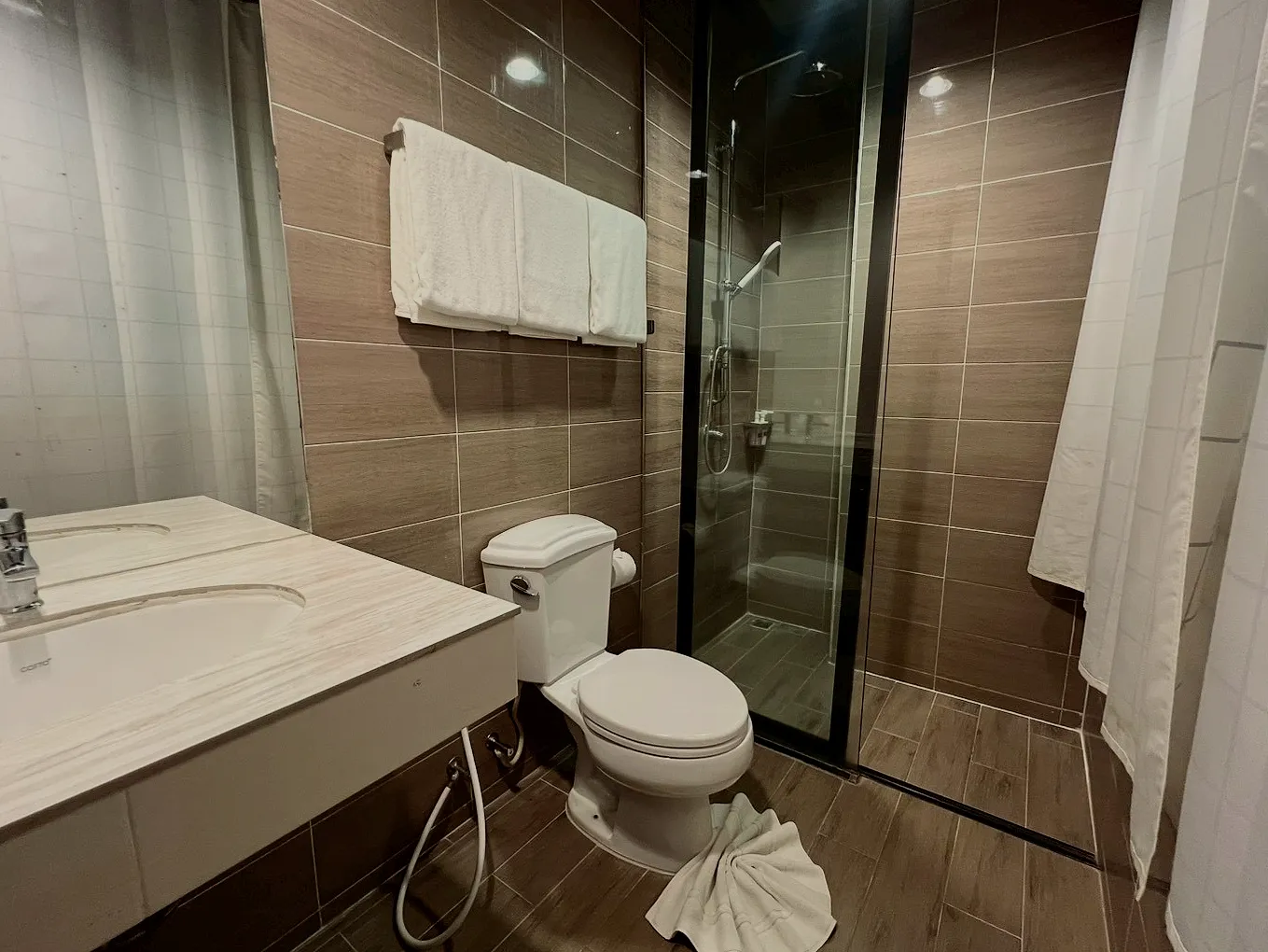 The bathroom: a white basin, a glass shower and folded towels.