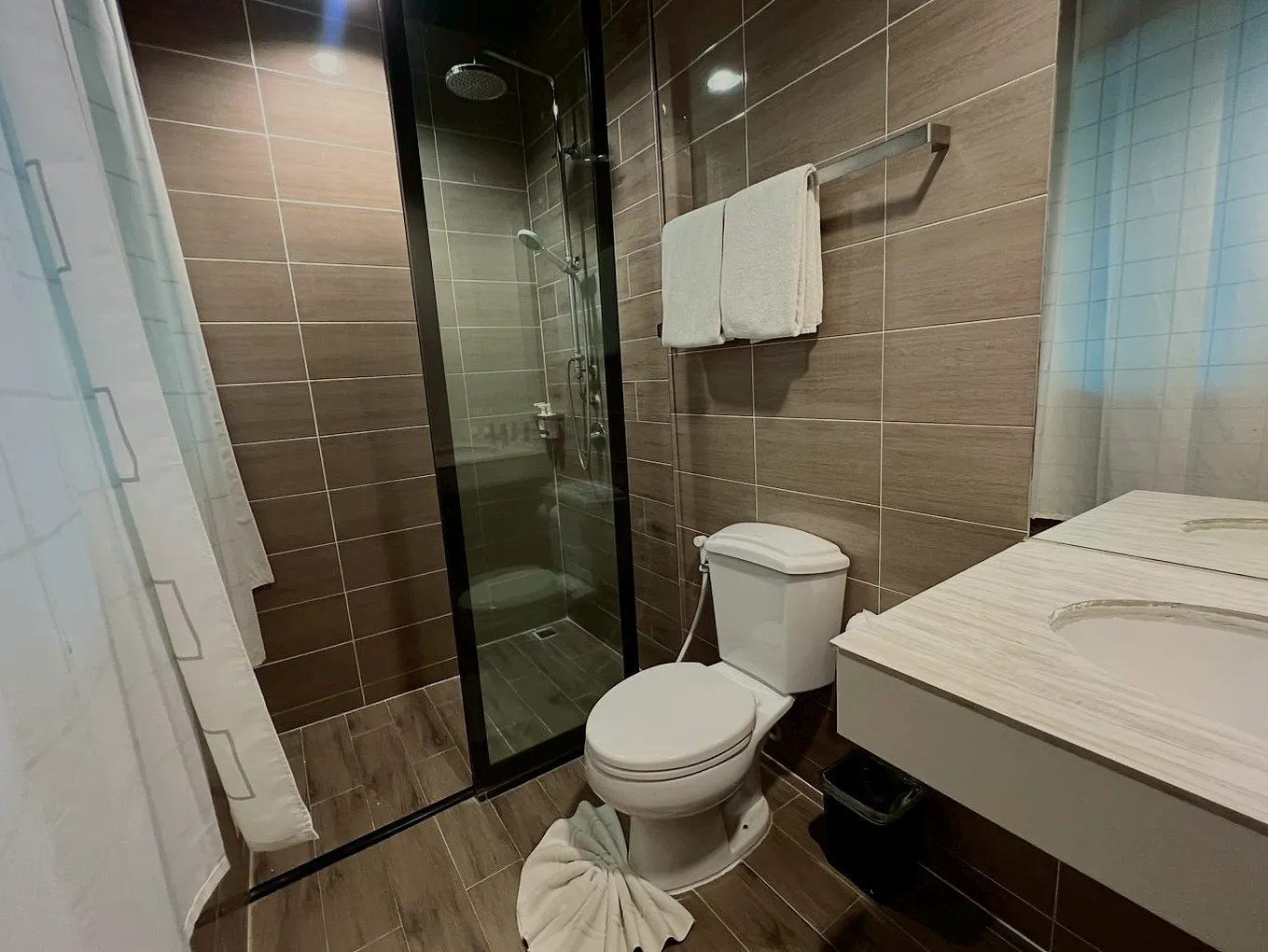 The bathroom: a glass shower, white towels and a basin.