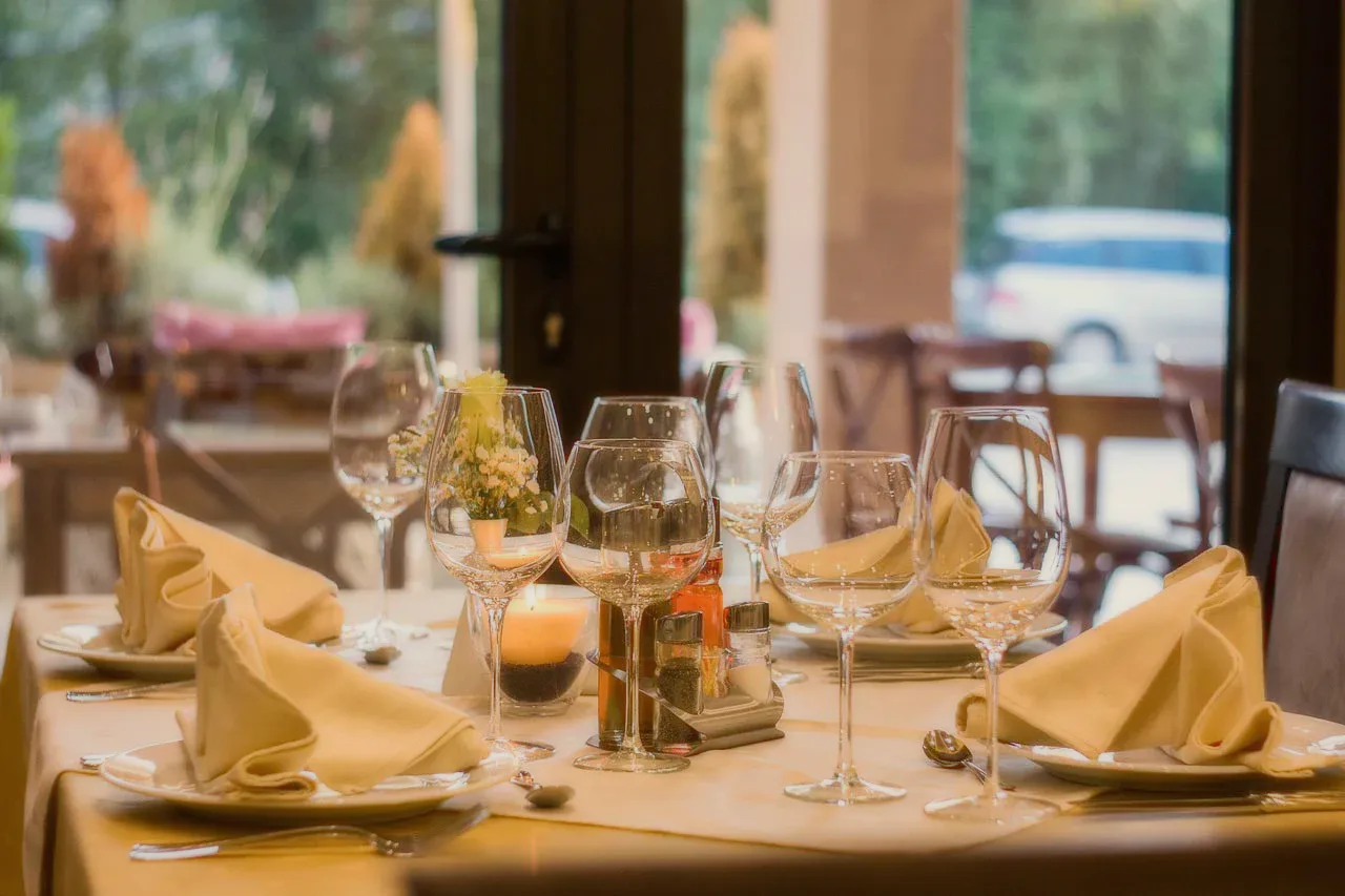 Wine glasses and folded napkins on a set restaurant table.