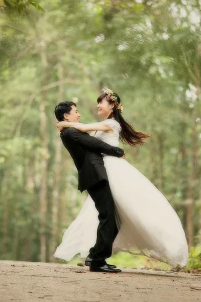 A bride and groom dancing among tall trees.